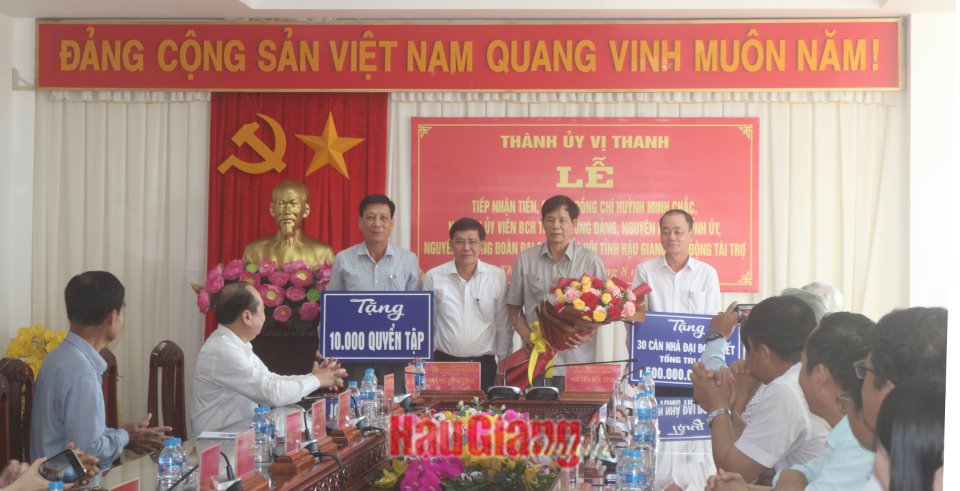 Ông Huỳnh Minh Chắc (thứ 2 từ phải sang), nguyên Bí thư Tỉnh ủy Hậu Giang, trao bảng tượng trưng tặng 30 căn nhà “Đại đoàn kết” và 10.000 quyển tập.